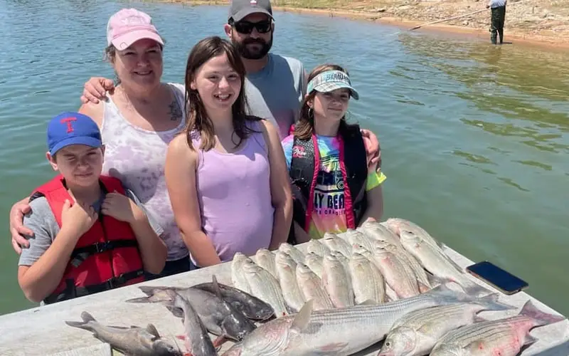 a family on the bay with striped bass fish laying on the table