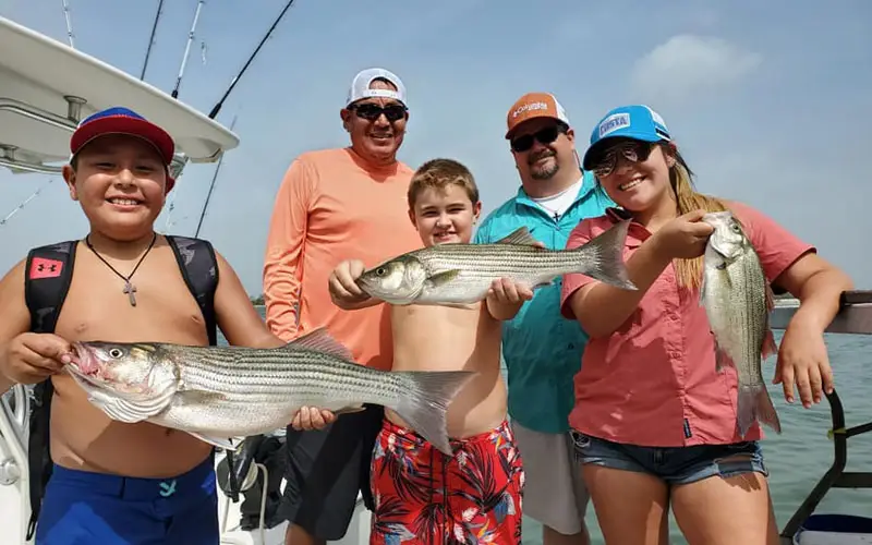 A family holding a striped bass fish