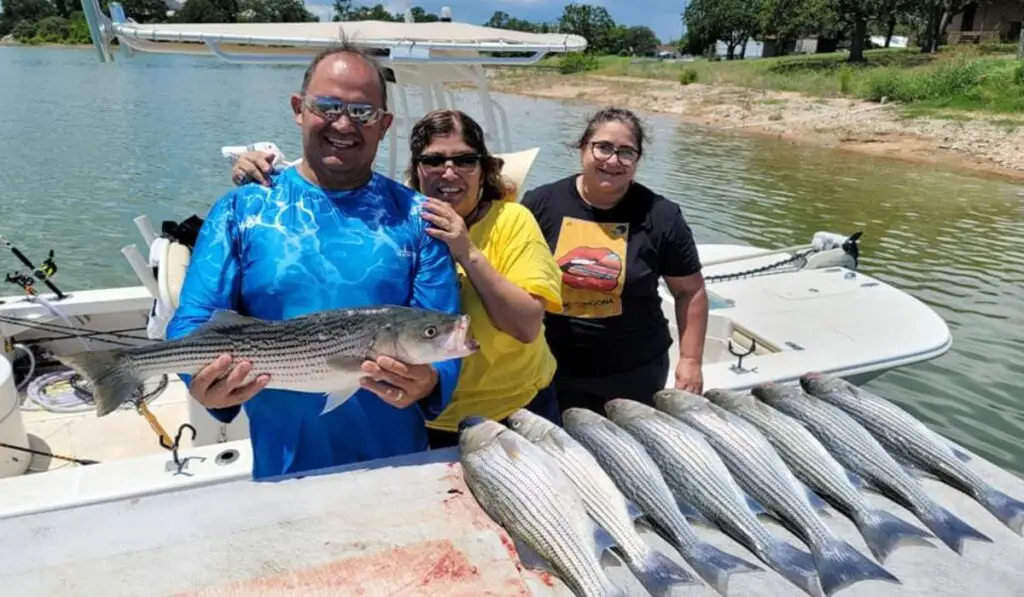 a man holding a large fish with two other women