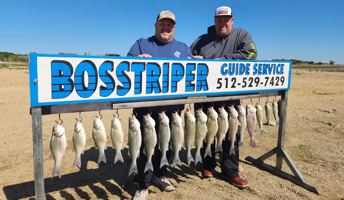 two men at Lake Buchanan holding signage of a fishing guide service