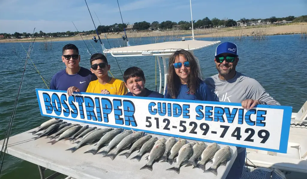 five people at Lake Buchanan holding signage of a fishing guide service
