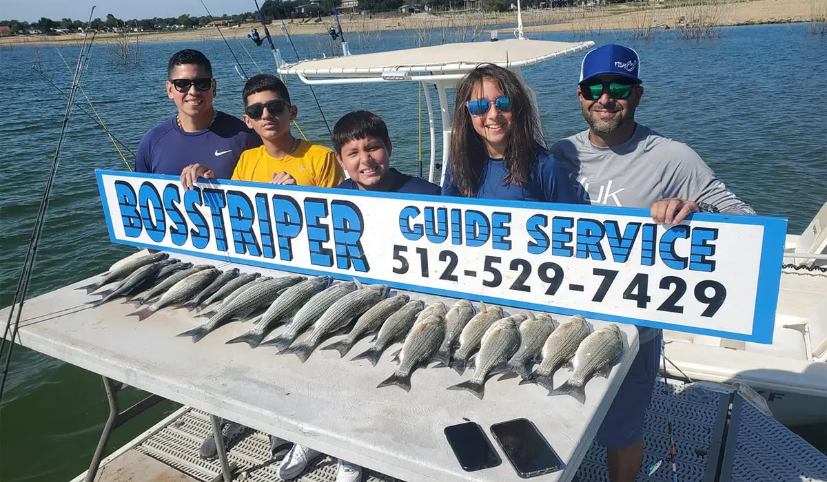 a family at Lake Buchanan holding signage of a fishing guide service